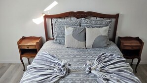 Una cama con una colcha estampada, dos almohadas y una manta a rayas.