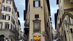 A narrow street with buildings on either side, featuring a shop with a visible entrance and signage. - Vintage apartments in the center of Florence (Florence)
