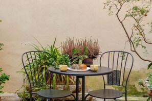 A round table with two chairs, surrounded by potted plants and a small table with cups and a decorative item. - Vintage apartments in the center of Florence (Florence)