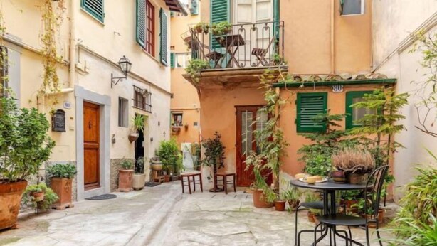 A narrow street with a small outdoor seating area, potted plants, and a building with a balcony. - Vintage apartments in the center of Florence (Florence)