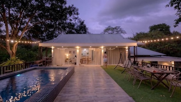 A pool with a tiled deck, a covered outdoor seating area, and string lights. - Khaoyai Valley8 (3BR-max 10 guests) (Pak Chong)