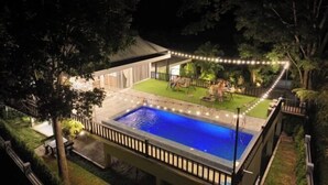 A swimming pool with a deck, surrounded by trees and a covered area with seating. - Khaoyai Valley8 (3BR-max 10 guests) (Pak Chong)