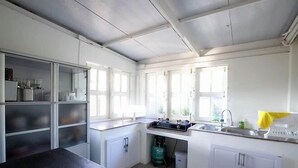 A kitchen with white cabinets, a black countertop, a sink, and a window. - Khaoyai Valley8 (3BR-max 10 guests) (Pak Chong)