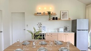 A dining table set with plates and glasses, a refrigerator, a coffee maker, and a plant on a shelf. - Khaoyai Valley8 (3BR-max 10 guests) (Pak Chong)