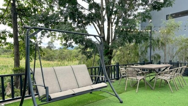 A patio with a swing, outdoor table, and chairs. - Khaoyai Valley8 (3BR-max 10 guests) (Pak Chong)