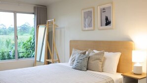 A neatly made bed with striped bedding, a bedside table with a lamp, and two framed pictures on the wall. - Khaoyai Valley8 (3BR-max 10 guests) (Pak Chong)