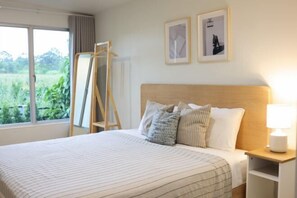 A neatly made bed with striped bedding, a bedside table with a lamp, and two framed pictures on the wall. - Khaoyai Valley8 (3BR-max 10 guests) (Pak Chong)