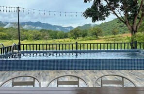 A swimming pool with a tiled edge, surrounded by a wooden deck and metal chairs. - Khaoyai Valley8 (3BR-max 10 guests) (Pak Chong)