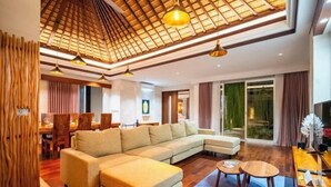 A modern living room with a sectional sofa, a dining area, and a large sliding glass door to a garden.