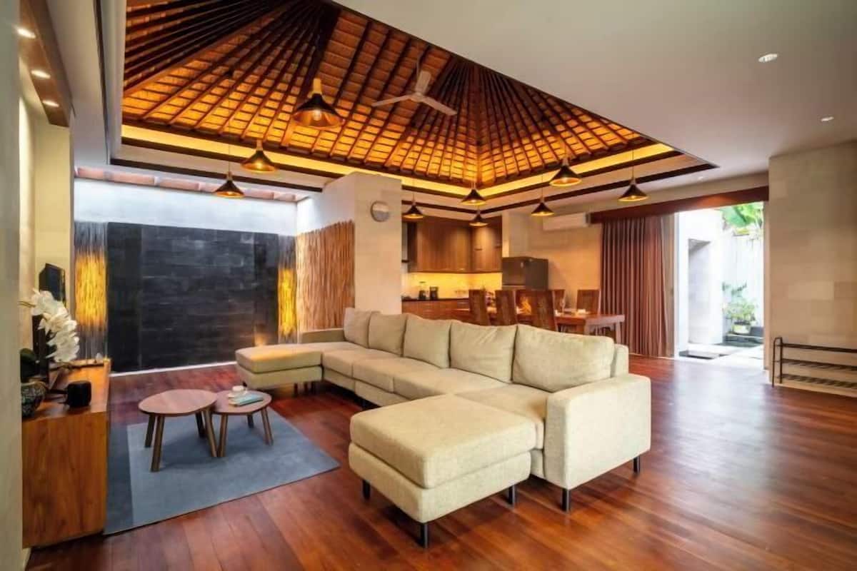 Un salon moderne avec un canapé d’angle, un plafond en bois et un coin repas.