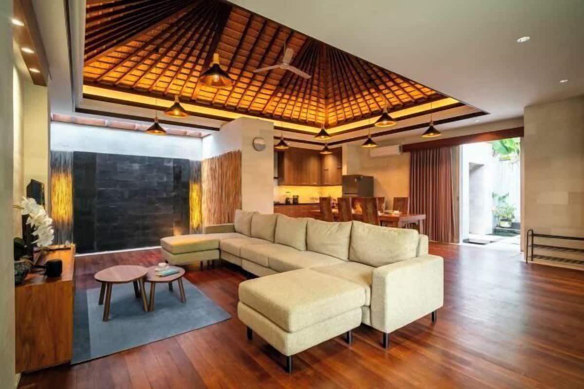 Un salon moderne avec un canapé d’angle, un plafond en bois et un coin repas.