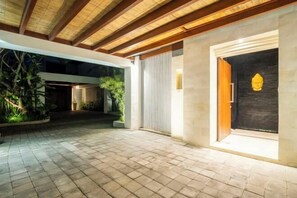 An outdoor area with a tiled floor, wooden ceiling beams, and a door with a golden statue. - Bali KBS Villas at Jimbaran Bay (Bali)