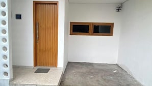 A room with a wooden door, a small window, and a concrete floor. - Home Stay Room In Bali (Bali)