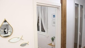 A hallway with a white door, a mirror, and a small plant on a shelf. - NEW, CENTRAL NEAR BEACH AND SEA by www.SanSebastianApartments.es (San Sebastian)