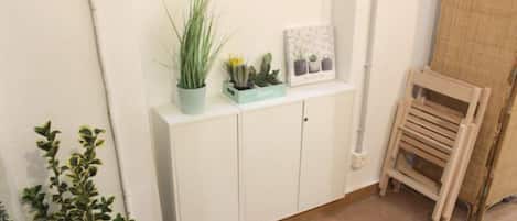 Un mueble blanco con una planta en maceta y un cuadro enmarcado.