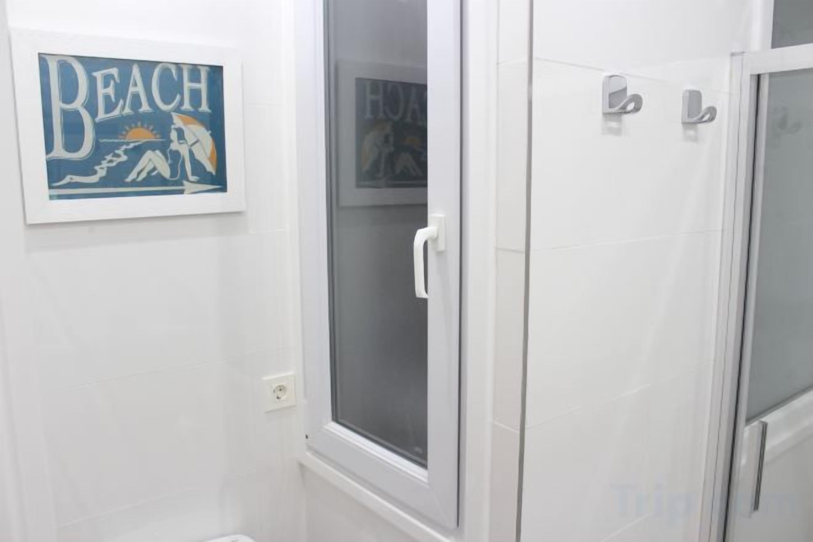 A bathroom with a shower, a toilet, and a framed picture on the wall.