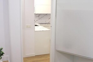 A hallway leading to a kitchen with white cabinets and a marble backsplash. - NEW, CENTRAL NEAR BEACH AND SEA by www.SanSebastianApartments.es (San Sebastian)