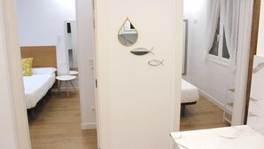 A hotel room with a bed, a small table, a mirror, and a window with curtains. - NEW, CENTRAL NEAR BEACH AND SEA by www.SanSebastianApartments.es (San Sebastian)