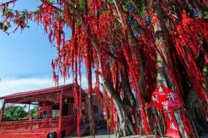 A tree with red decorations, a red building, and a sign with white text. - Secret Garden Homestay (Kuala Selangor)