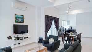Uma sala de estar moderna com televisão de tela plana, um sofá, uma mesa de centro e um espaço de jantar com mesa e cadeiras.