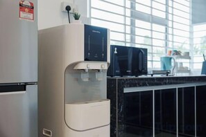 A kitchen with a water dispenser, a microwave, and a coffee maker. - Secret Garden Homestay (Kuala Selangor)