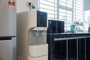 Una cocina con dispensador de agua, microondas y cafetera.