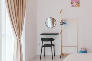 A bedroom with a bed, a desk with a chair, a mirror, a coat rack, and a small shelf. - Secret Garden Homestay (Kuala Selangor)