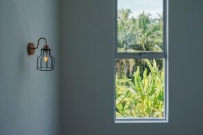 A room with a window overlooking a lush garden. - Secret Garden Homestay (Kuala Selangor)