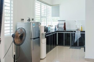 Una cocina con refrigerador, microondas y pileta.