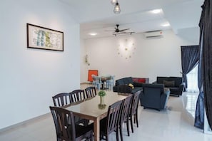 Una sala moderna con comedor, ventilador de techo y un gran ventanal con cortinas.