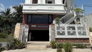 A multi-story hotel with a prominent entrance, balconies, and a clear sky. - OYO 1296 Phu Loc Xuan Hotel Danang (Da Nang)