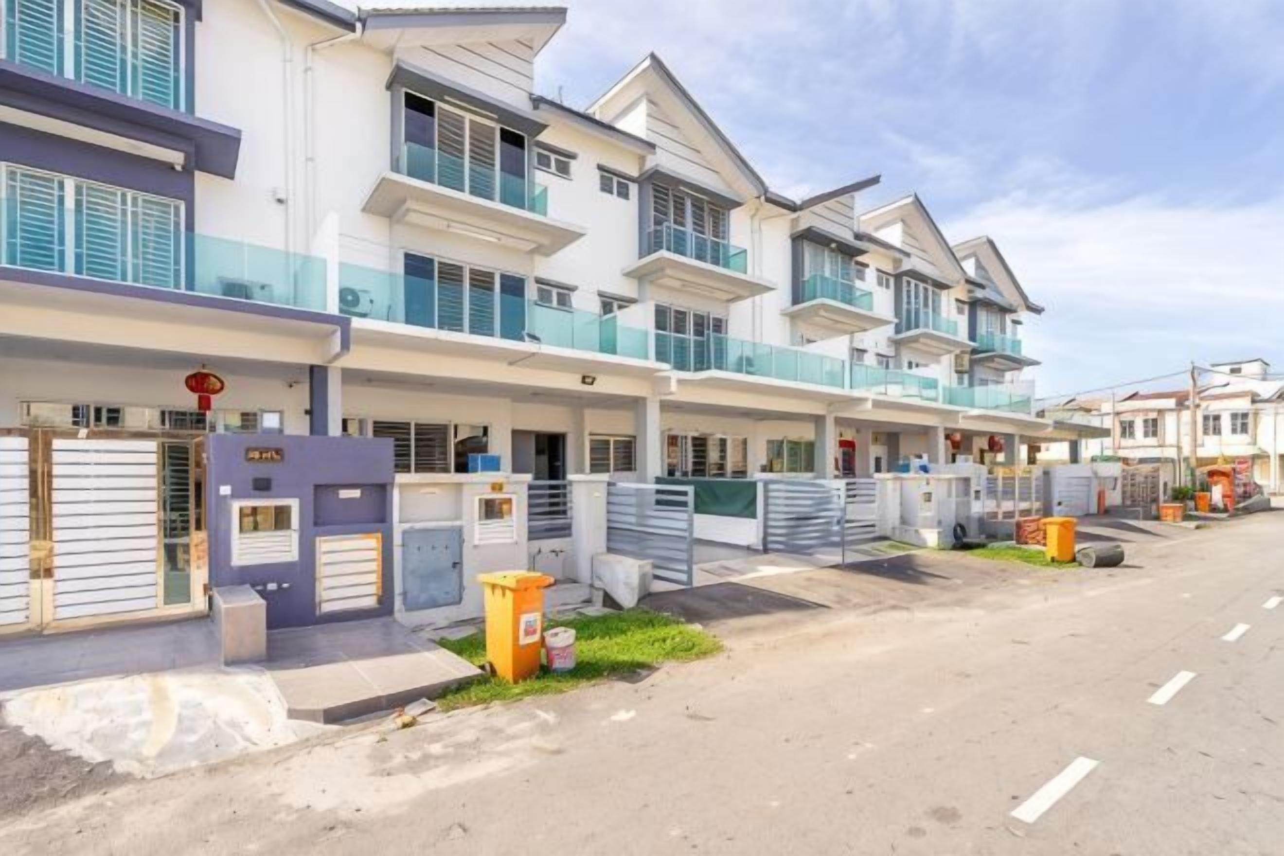 A row of modern multi-story residential buildings with balconies, a gated entrance, and a clear sky.