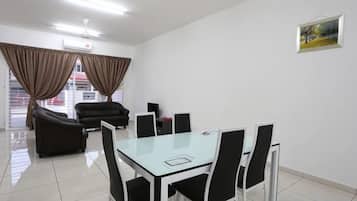 A modern room with a glass table and chairs, a sofa, and a TV.