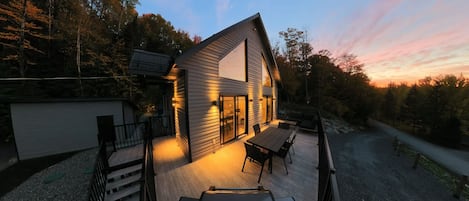 Et moderne hus med terrasse, store vinduer og udsigt til den omkringliggende skov.