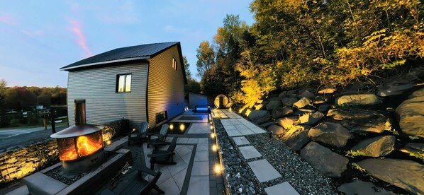 A modern house with a fireplace, outdoor seating, and a stone pathway.