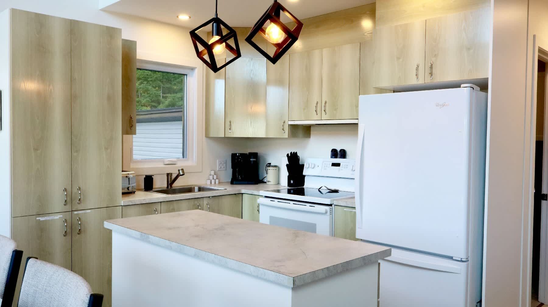 A modern kitchen with wooden cabinets, a white refrigerator, and a central island.