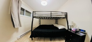 A bunk bed with a desk and lamp, a window with curtains, and a thermostat on the floor. - Spa, Sauna, Lake and Pool table | The Dorchester (Saint-Prosper)