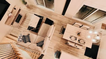 Een moderne woonkamer met een bank, salontafel en een eetgedeelte met een kroonluchter.