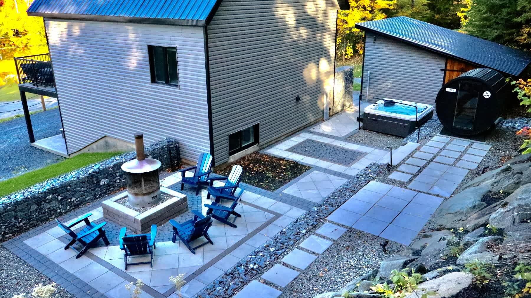 Un área de patio con mobiliario exterior, una chimenea y un jacuzzi.