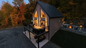 A modern house with a balcony, a stone wall, and a fire pit area.