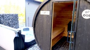 A wooden sauna with a bench inside, a door with a sign, and a metal frame. - Spa, Sauna, Lake and Pool table | The Dorchester (Saint-Prosper)