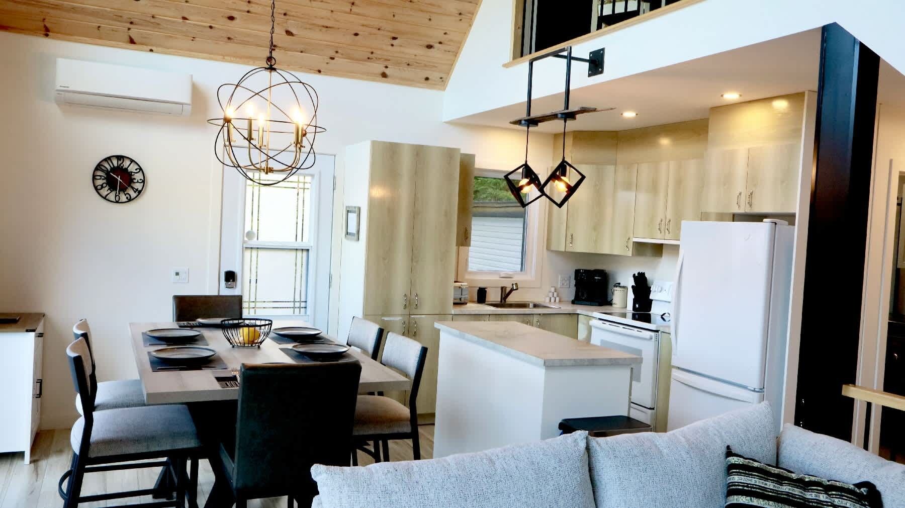 Una cocina moderna con comedor, que incluye una araña, un reloj y un refrigerador.