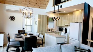 A modern kitchen with a dining area, featuring a chandelier, a clock, and a refrigerator. - Spa, Sauna, Lake and Pool table | The Dorchester (Saint-Prosper)