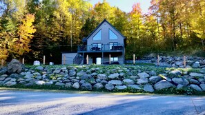 A two-story house with a balcony, surrounded by a stone wall and a forest. - Spa, Sauna, Lake and Pool table | The Dorchester (Saint-Prosper)
