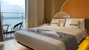 Una habitación de hotel con cama, mesita de noche, silla y vista al agua.