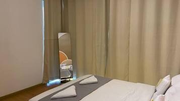 A hotel room with a bed, a mirror, and curtains.
