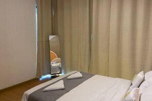 A hotel room with a bed, a mirror, and curtains.