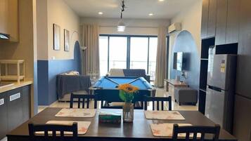 A modern living room with a pool table, dining table, and kitchen area.