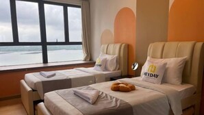 Habitación de hotel con dos camas, vista al mar y una almohada 'HEYDAY' en una de ellas.