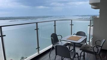 A balcony with a table and chairs overlooking a body of water.